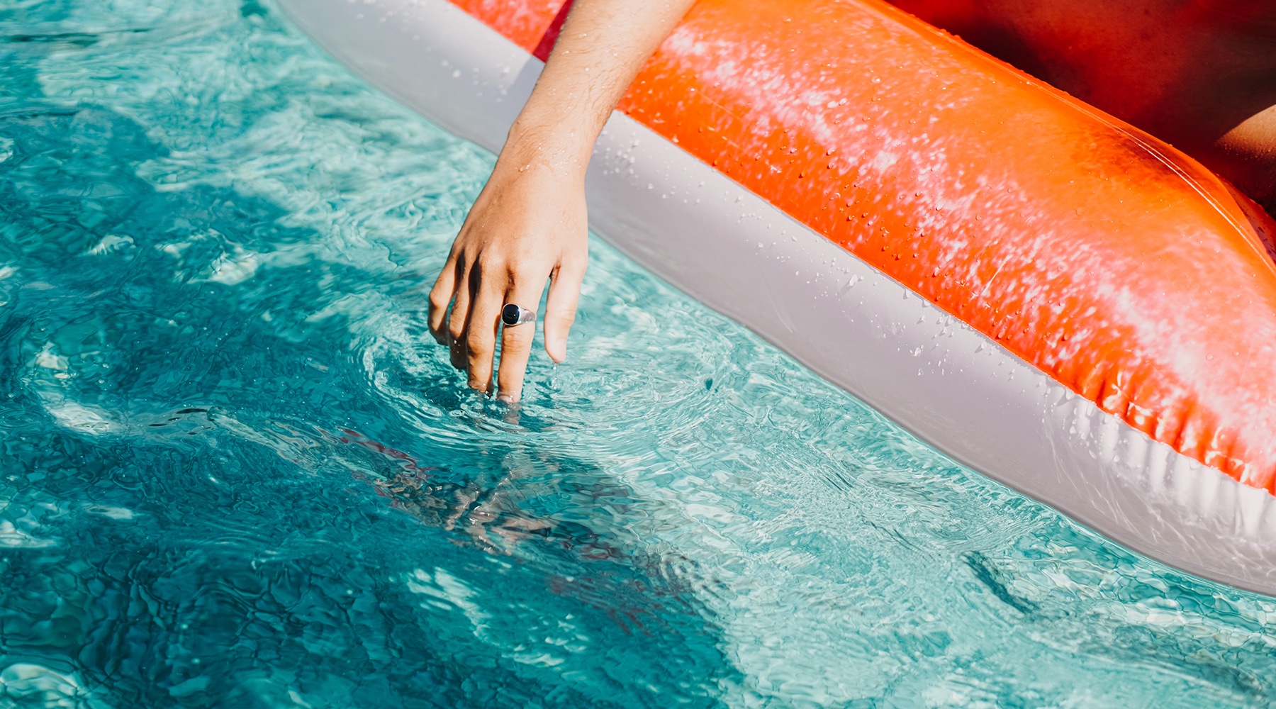 a woman's hand dipping in a pool